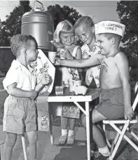  ?? THE COMMERCIAL APPEAL ?? Freddy Raby, right, 6, sets up his lemonade stand in his front yard every afternoon. Three of his best customers, from left, Gary Atkinson, 3, Janet Atkinson, 5, and Paul Payne, 6, stopped by to sip a 2-cent cupful and watch Freddy put his profits in his piggy bank cash register on July 26, 1952.