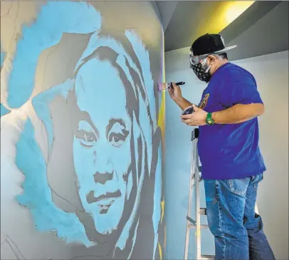  ?? L.E. Baskow Las Vegas Review-journal @Left_eye_images ?? Artist Miguel Hernandez paints a mural Jan. 29 in memory of Tony Hsieh in the lobby of Art Houz Theaters.