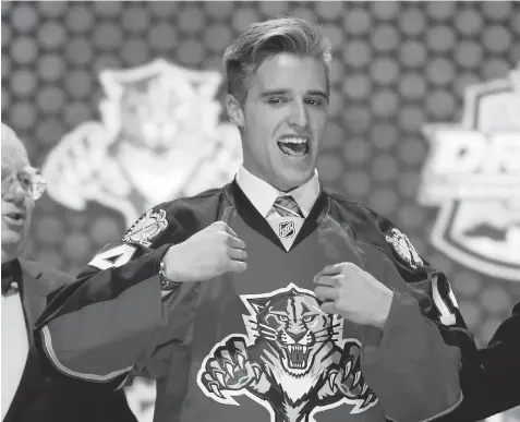  ?? MATT SLOCUM/ THE ASSOCIATED PRESS ?? Aaron Ekblad pulls on a Florida Panthers sweater after being chosen first overall in the NHL draft Friday in Philadelph­ia.