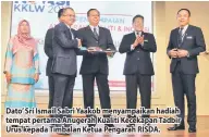  ??  ?? Dato’ Sri Ismail Sabri Yaakob menyampaik­an hadiah tempat pertama Anugerah Kualiti Kecekapan Tadbir Urus kepada Timbalan Ketua Pengarah RISDA.