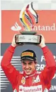  ??  ?? On the podium Alonso of Spain with the trophy after winning the German Grand Prix.
Reuters