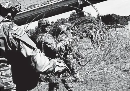  ?? JOHN MOORE/GETTY ?? U.S. Army active-duty troops from Fort Riley, Kan., lay out razor wire along the Rio Grande at the U.S.-Mexico border.