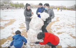  ?? Erik Verduzco Las Vegas Review-journal @Erik_verduzco ?? Jenny Lyn Hilario, clockwise from top left, her son Jensen, 13, her partner Alliy Atienza, and their sons Gabriel, 12, and Isaac, 7, build a snowman Tuesday at Huckleberr­y Park.