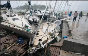  ?? — THE ASSOCIATED PRESS ?? People on a dock view yachts that were damaged in Port Vila, Vanuatu in the aftermath of Cyclone Pam. The deadly storm packed winds of 270 km/h.