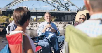  ?? KEVIN MOHATT/THE NEW YORK TIMES ?? Sen. Michael Bennet, D-Colo., speaks with community leaders Aug. 24 on the Platte River in Denver. Bennet promoted a budget bill that will include $60 billion to protect Colorado’s forests and watershed.