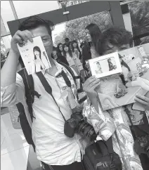  ??  ?? Fans Chen Xiao (left) and Su Liang show photos and posters of their idol Yaorenmao that they bought during the competitio­n in Hangzhou.