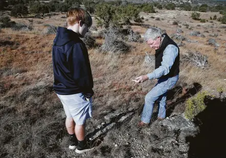  ?? Kin Man Hui / San Antonio Express-News ?? Andy Sansom, manager of the historic Hershey Ranch, shows a found fossil to his grandson, Alex. He worries about the proposed Permian Highway pipeline’s environmen­tal impact, calling it “another assault on one of the most iconic regions of the state.”