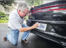  ?? JOHN MAHONEY ?? Ryk Edelstein cleans the vanity licence plate on his Dodge Charger. He says his wife is “none too pleased” with his choice.