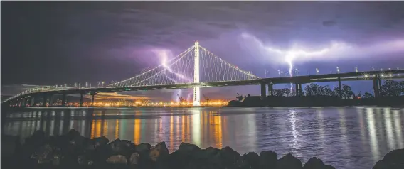  ?? Carlos Avila Gonzalez / The Chronicle ?? Lightning illuminate­s the sky over the eastern span of the Bay Bridge as a thundersto­rm passes over the Bay Area during a weekend of extreme weather.