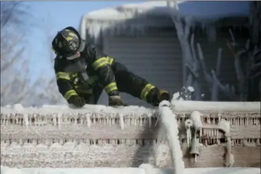  ?? AP FILE PHOTOS ?? A Newark, N.J., firefighte­r kicks free a hose frozen onto a roof of a building after helping battle a five-building fire Jan. 5.