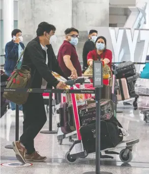  ?? FRANK GUNN / THE CANADIAN PRESS ?? Passengers from an Air India flight from New Delhi wait for their transporta­tion
to quarantine after arriving at Pearson Airport in Toronto on Wednesday.