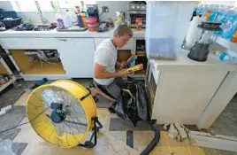  ?? CHRIS O’MEARA/AP ?? Jordan Cromer gathers waterlogge­d items at his home Tuesday in North Port, Fla. Florida residents continue to clean up damage caused by Hurricane Ian.