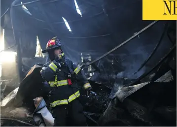  ?? AHMAD GHARABLI / AFP / GETTY IMAGES ?? A firefighte­r inspects damage in Beit Meir, a village in central Israel where hundreds were evacuated following the spread of wildfires this week. Authoritie­s are investigat­ing the cause of the blaze that left damage across the country.