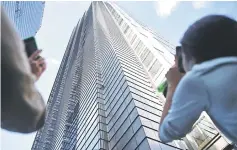  ?? — AFP photos ?? People look up at Robert climbing Heron Tower, 110 Bishopsgat­e, in central London, the tallest tower in the city of London.