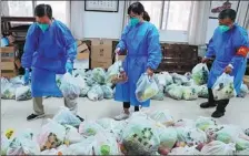  ?? YAN TONG / FOR CHINA DAILY ?? Community workers sort free packs of vegetables for residents quarantine­d at home in Haidian district, Beijing, on Sunday.