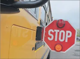  ?? ADAM MACINNIS ?? When the red lights are flashing on a school bus and the stop sign is extended, cars must stop. Passing a bus in these circumstan­ces is illegal.