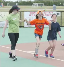  ?? JASON KRYK ?? Miracle League of Amherstbur­g player Arta Giles, centre, runs toward home plate with buddies Faith Vennell, left, and Hailey Connor.