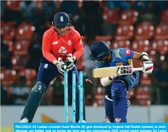  ?? —AFP ?? PALLEKELE: Sri Lankan cricketer Kusal Mendis (R) gets dismissed by England Adil Rashid (unseen) as wicketkeep­er Jos Buttler look on during the third one day internatio­nal (ODI) cricket match between Sri Lanka and England at the Pallekele Internatio­nal Cricket Stadium in Pallekele yesterday.