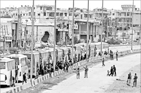  ??  ?? Syrian forces are seen around buses as civilian and rebels prepare to leave outside Harasta in eastern Ghouta in Damascus, Syria. — Reuters photo