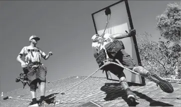  ?? Anne Cusack Los Angeles Times ?? CALIFORNIA IS pushing toward a carbon-free grid. Current mandates call for 50% of electricit­y produced by clean energy by 2030. Above, Tyler Smith, left, and Randy Murray install panels in Camarillo in 2013.