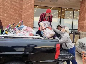  ?? [PHOTOS BY PAULA BURKES, THE OKLAHOMAN] ?? “Elves” David, Trish and Amanda, from left, load a client’s truck with toys.