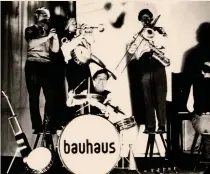  ??  ?? Opere e protagonis­tiIn alto, la «Bauhaus Band» durante un concerto nel 1930 e il Manifesto del Bauhaus (aprile 1919, xilografia di Lyonel Feininger con la grande Cattedrale simbolo di unità delle arti). Accanto nel testo, i Maestri del Bauhaus sul tetto della Scuola a Dessau nel 1926, con il fondatore e direttore Walter Gropius al centro. In basso, l’edificio del Bauhaus progettato da Walter Gropius a Dessau (1925-26)