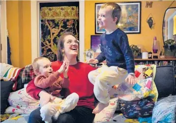  ?? ROBERT F. BUKATY/AP ?? Heather Cimellaro holds her son, Charlie, while his twin brother, Milo, jumps Wednesday at their home in Auburn, Maine. With the 3-year-olds too young for COVID-19 shots, Cimellaro is concerned about the omicron-driven surge in cases.
