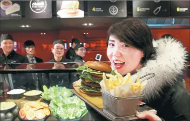  ?? JIANG DONG / CHINA DAILY ?? A customer shows a self- made burger at McDonald’s first Experience of the Future restaurant in Beijing.