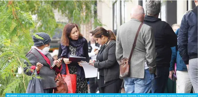  ??  ?? MELBOURNE: A Centrelink worker (center) speaks to some of the hundreds of people queued outside an Australian government welfare center, Centrelink, in Melbourne yesterday as jobless Australian­s flooded unemployme­nt offices around the country after Prime Minister Scott Morrison warned the coronaviru­s pandemic would cause an economic crisis akin to the Great Depression.— AFP