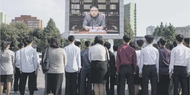  ?? PICTURE: ED JONES ?? Spectators watch North Korean leader Kim Jong-un, read a statement on a public television screen in the capital Pyongyang