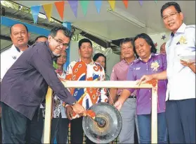  ??  ?? Hasbi (left) beats the gong to officiate at the opening of the SK Kuala Mendalam’s sports meet, witnessed by Brain (second left), Jelia (second right) and Endrick (right).