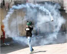  ?? Photo: AFP ?? A Palestinia­n demonstrat­or throws back a teargas canister towards Israeli forces during clashes in Hebron.