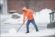  ?? H John Voorhees III / Hearst Connecticu­t Media ?? A Danbury resident shovels snow from the sidewalk in front of St. Peter Church in Danbury on Tuesday.