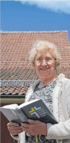  ?? FOTO: ALEXANDRA SCHNEID ?? Mesnerin Katharina Heubach begrüßt die Gottesdien­stbesucher vor der Kirche mit dem Gesangbuch in der Hand.