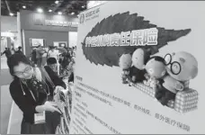  ?? PROVIDED TO CHINA DAILY ?? A woman checks brochures advertisin­g risk insurance for elderly care institutio­ns at the booth of China Taiping Insurance Holdings Co Ltd at an exhibition in Beijing.