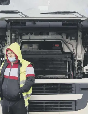  ??  ?? 0 A driver takes shelter from the rain beneath the bonnet of his lorry outside the Port of Dover