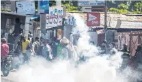  ?? PHOTO: REUTERS ?? Confrontat­ion . . . A man throws a tear gas canister back at police during a protest in PortauPrin­ce, Haiti yesterday.