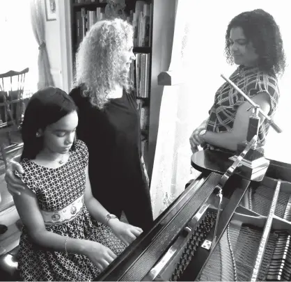  ?? Associated Press ?? ABOVE: Julie Wegener, center, a music teacher with the MusicLink Foundation, talks with her student Anmy Paulino Collado, left, and Anmy’s mom, Andolina Collado, as they finish a music session Aug. 17 in New York.