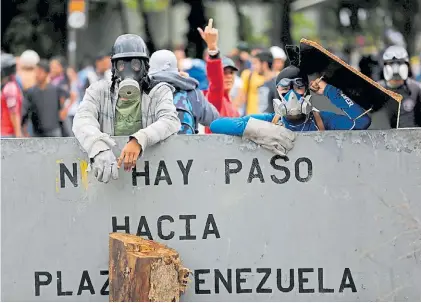  ?? REUTERS ?? Bloqueo. Con máscaras antigas, manifestan­tes cierran el tránsito durante una protesta en Caracas.