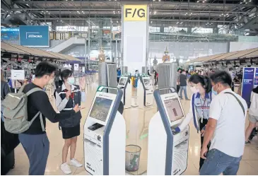  ?? ARNUN CHONMAHATR­AKOOL ?? Passengers prepare to depart at Suvarnabhu­mi airport via self check-in kiosks.