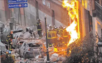  ?? Manu Fernandez The Associated Press ?? Firefighte­rs carry a body next to a damaged building after an explosion Wednesday in downtown Madrid.