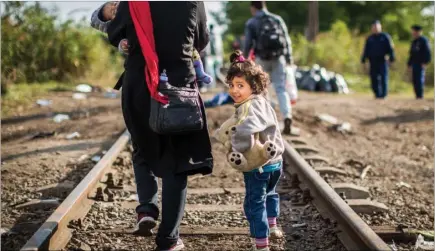  ?? Picture: SWNS.COM ?? An girl from Afghanista­n walks with a group of refugees along ailway lines to cross the border to Hungary from Serbia