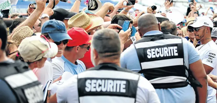  ?? Picture: Getty Images ?? Security surrounds Lewis Hamilton as he signs autographs for fans in the pit lane ahead of the Formula One Grand Prix of France at Circuit Paul Ricard.