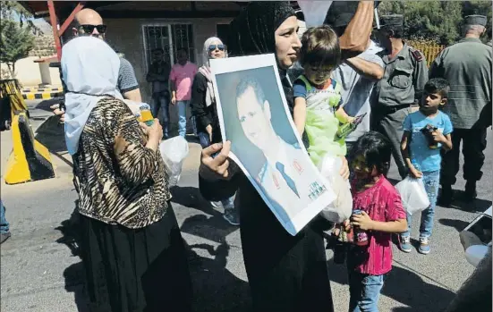  ?? GONZALO ARAGONÉS ?? Una mujer, recién retornada a Siria con su familia por el puesto fronterizo de Zhdaidet Yabus, con Líbano, muestra una foto de El Asad