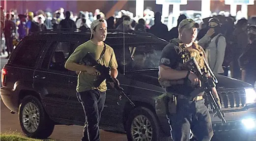  ?? ADAM ROGAN/THE JOURNAL TIMES VIA AP ?? Kyle Rittenhous­e (left) walks along Sheridan Road in Kenosha, Wisconsin, with another armed civilian on Aug. 25. Rittenhous­e, 17, of Antioch, is accused of killing Anthony Huber and Joseph Rosenbaum during protests over the police shooting of Jacob Blake.