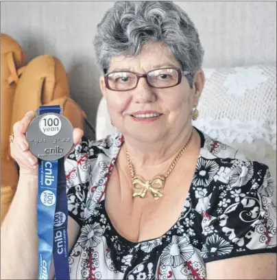  ?? SALLY COLE/THE GUARDIAN ?? Marguerite Keating, president of the P.E.I. Ladies Auxiliary of the CNIB, shows a Century of Change medal presented to her organizati­on, during the CNIB’s 100th birthday party, this past March. The medal was awarded to individual­s and organizati­ons who...