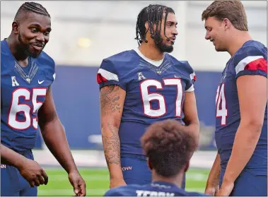  ??  ?? Top, UConn redshirt junior Brian Cespedes (67, middle), a New London High School graduate, talks with teammates during football media day Tuesday at the Shenkman Training Center. Left, UConn defensive coordinato­r Billy Crocker is a Waterford native, giving the Huskies’ coaching staff three former Eastern Connecticu­t Conference standouts.
