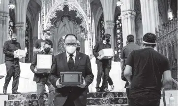  ?? EDUARDO MUNOZ ALVAREZ AP ?? Jorge Islas Lopez, Consul General of Mexico, and others carry the remains of loved ones following the blessing of the ashes of Mexicans who died from COVID-19 at St. Patrick’s Cathedral on Saturday in New York City. The ashes were blessed before they were repatriate­d to Mexico.