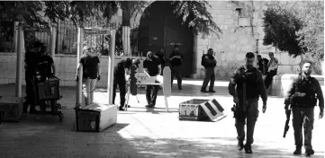  ??  ?? Israeli border policemen install metal detectors outside the Lion’s Gate, a main entrance to Al-Aqsa mosque compound, in Jerusalem’s Old City after security forces reopened the ultra-sensitive site. — AFP photo