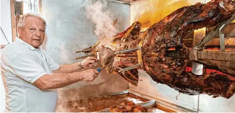  ?? Foto: Peter Fastl ?? Morgens um vier Uhr hat Metzger Eberhard Frieß den Grill eingeschal­tet. Mit einem Messer schneidet er große Scheiben vom Braten ab, die dann noch etwas im Fleischsaf­t ruhen dürfen, bevor sie auf die Teller kommen.